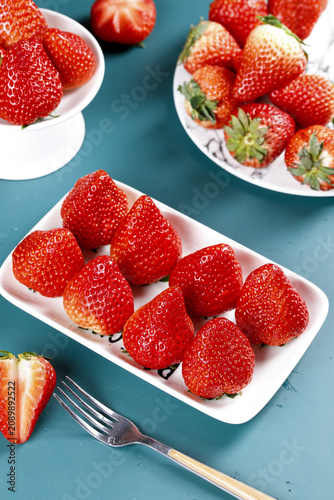 Tableau sur toile Fresh Ripe Strawberries in White Dishes on Turquoise Background - Healthy Vitami