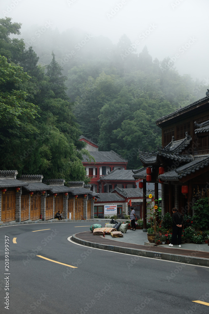 Fototapeta premium Traditional Chinese Buildings in Wudang Mountains with Misty Forest and Mountain Road