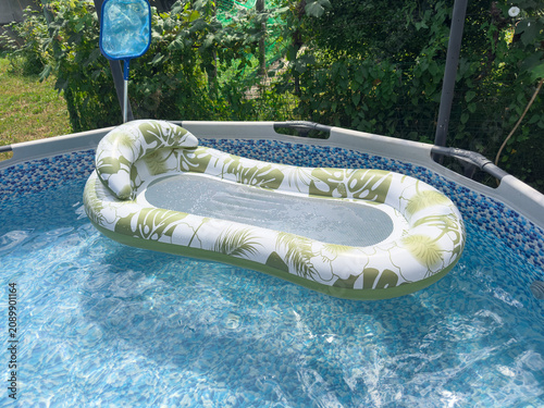 Obraz na płótnie Young woman relaxing on a floating air mattress in a backyard pool