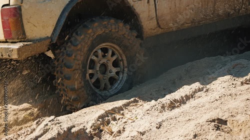 A close-up of a powerful 4x4 vehicle skidding through sand. Sand flies off the tires during an off-road race. Action-packed shot