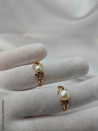 Jeweler hand in white cotton glove holding two gold pearl rings. Professional jewelry inspection and appraisal concept