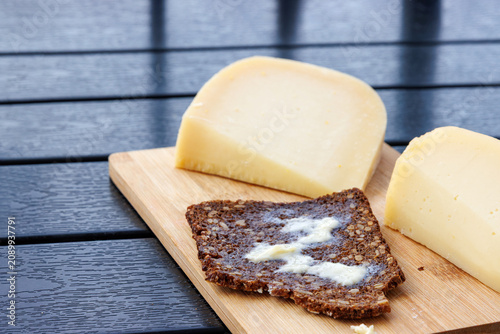 Sourdough wholegrain rye bread  with melting butter, served with cheese on a wooden board.