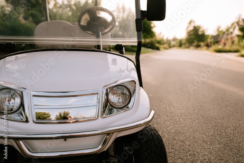 Suburban roadway with a white golf cart paused on the road, daylight and calm vibe