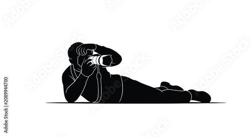Tableau sur toile Lying photographer with camera black silhouette against a white background silho