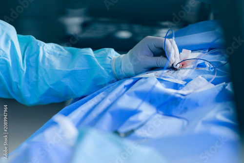 Fotografie Closeup of surgeon hand during cardiac catheter insertion showing hub and steril