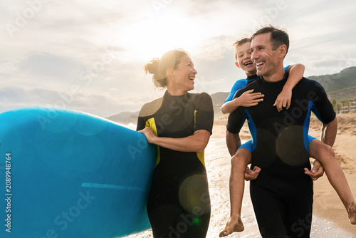 Quadro su tela Family enjoying beach vacation learning to surf together