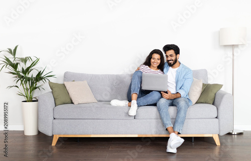 Foto Loving happy beautiful eastern couple in stylish casual outfit sitting on couch