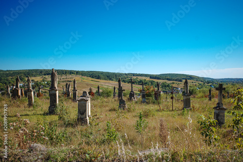 Old rural cemetery with weathered stone gravestones in overgrown grass