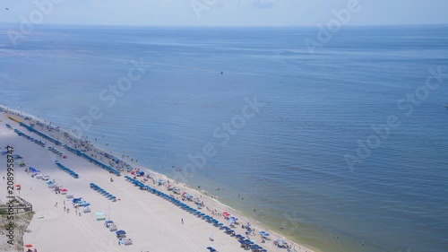 Stunning aerial view of the white sand beach in Orange Beach / Gulf Shores, Alabama during summer. Colorful umbrellas and chairs line the shore along the turquoise Gulf of Mexico / America waters