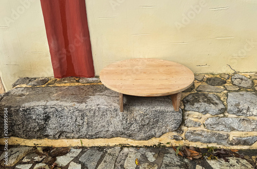 Authentic low circular wood Sofras table on stone steps. Traditional Mediterranean vintage furniture used for dining and baking in historic Crete.