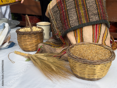 Traditional outdoor still life featuring ancient zea grains and wheat in woven baskets, a vintage woven sack and flour. Ideal for authentic heritage, baking and Mediterranean diet themes. Empty space.