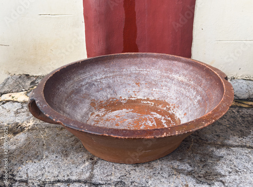Authentic vintage Greek Lekanida earthenware bowl on stone wall. Traditional Mediterranean rustic pottery used for washing or cooking in old Crete.
