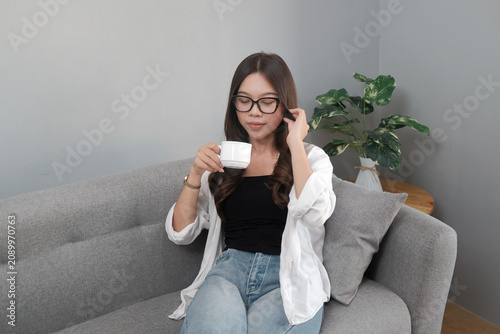 Young Asian Indonesian Woman Enjoying Coffee Break on Comfortable Sofa