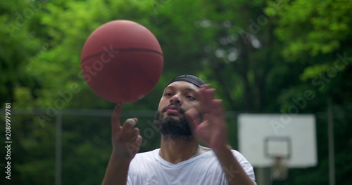 Photography African American man spinning basketball close-up on finger, expression of focus