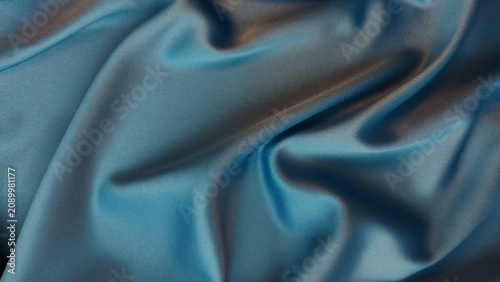 Fotografie Blue silk fabric with elegant flowing folds in studio