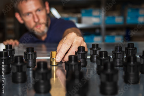 Cuadro en lienzo Warehouse worker placing a single brass threaded pipe fitting among rows of blac
