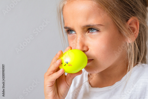 Foto Young girl holds a bright yellow sensory toy close to her nose, appearing to rea