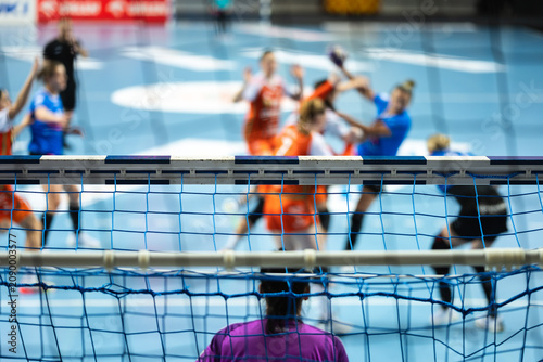Photos Detail of handball goal crossbar with net and women handball match in the background