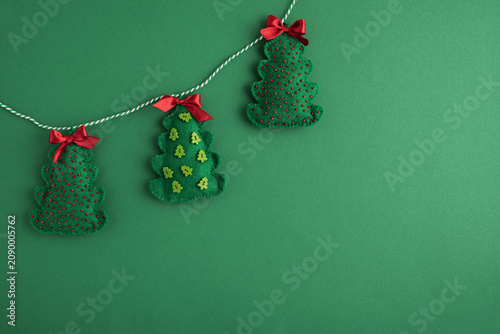 Handcrafted felt christmas tree garland against a green background