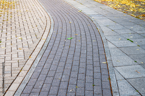 Bicycle lane made of paving stones forming a curved path. Bicycle path paved with distinct grey and beige concrete cobblestones in an urban environment