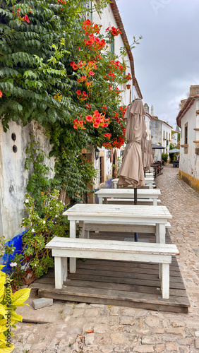 Outdoor seating area in a quiet street with plants and umbrellas on a cloudy day, Portugal