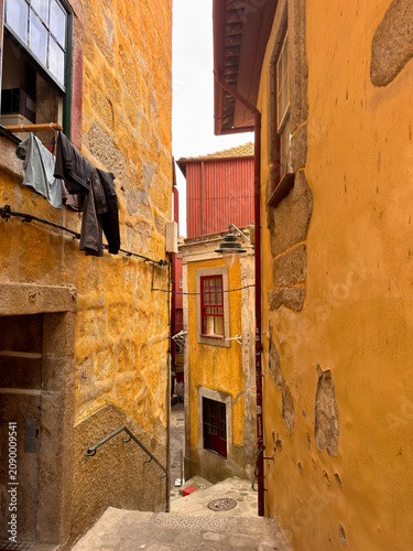 Narrow alley with colorful buildings and hanging clothes near Porto in Portugal during a cloudy day