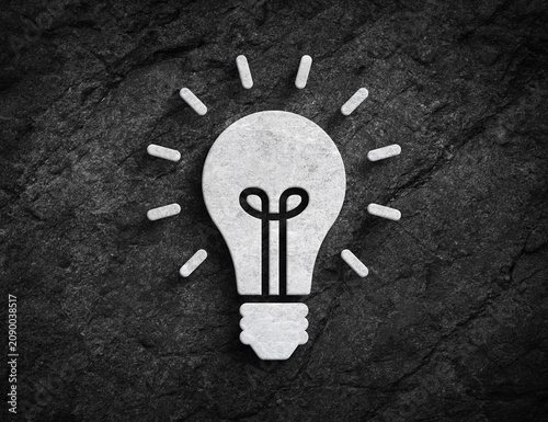 Glowing lightbulb idea symbol carved on stone wall