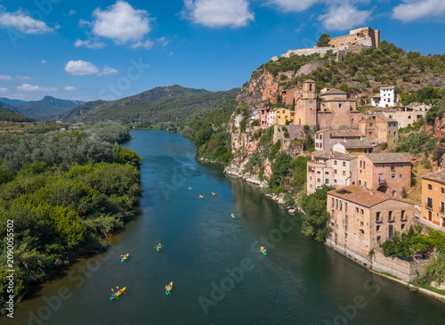 Obraz na plátně Group of kayakers in yellow boats paddling along the Ebro River beside the histo