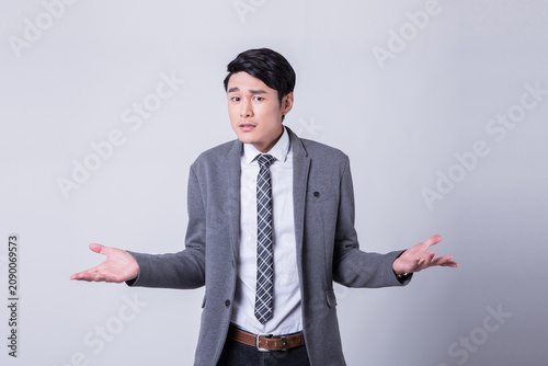 Quadro su tela Confused young businessman shrugging with uncertain expression