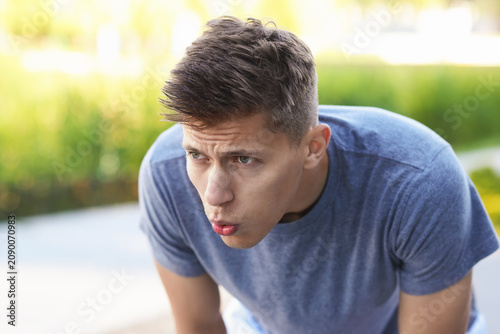 Tired man sweating after workout in park, space for text