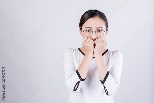 Foto Anxious young woman biting nails in fearful studio portrait