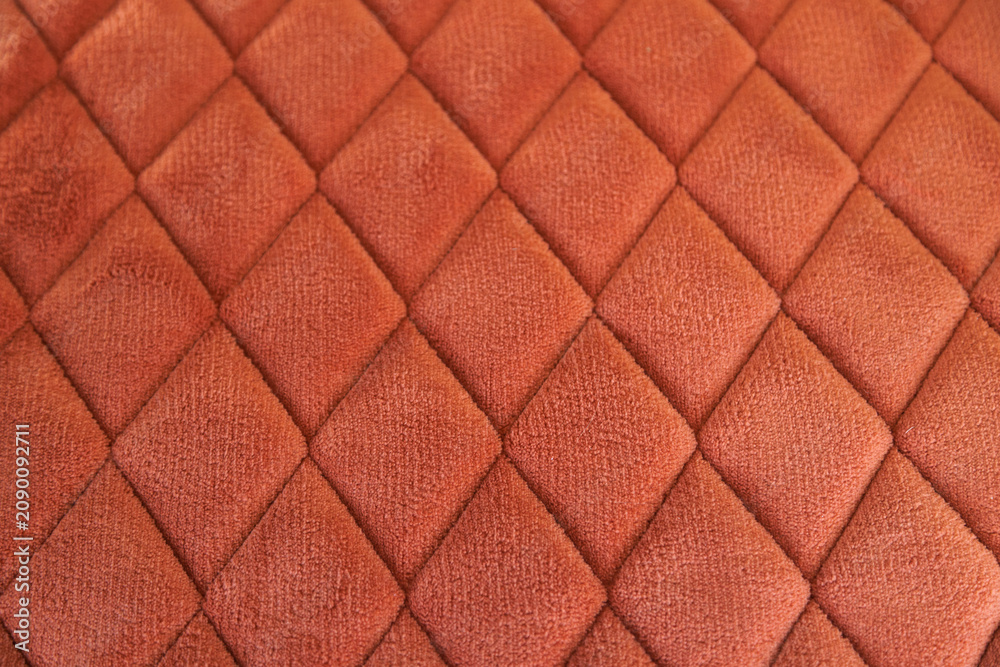 Obraz premium Orange velvet quilted fabric creating diamond pattern