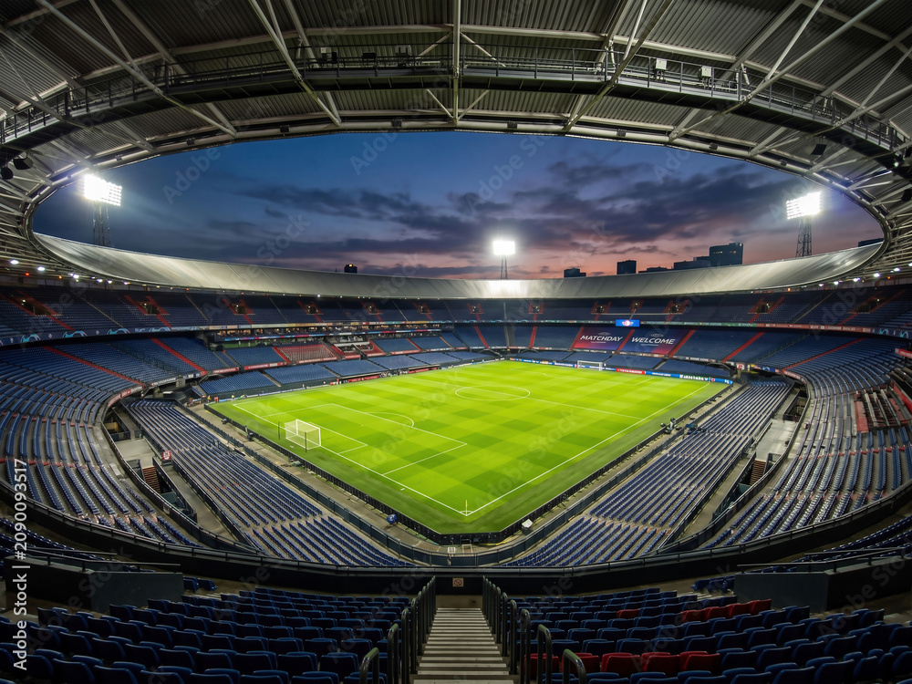 Naklejka premium Empty football stadium under bright lights at sunset