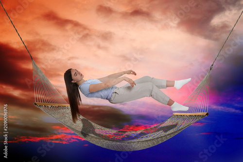 Foto Young sleeping woman falling into hammock against bright sky