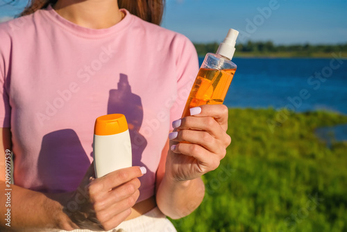 Bild auf Leinwand Woman choosing between sunscreen lotion and tanning oil spray for summer skincare and sun protection