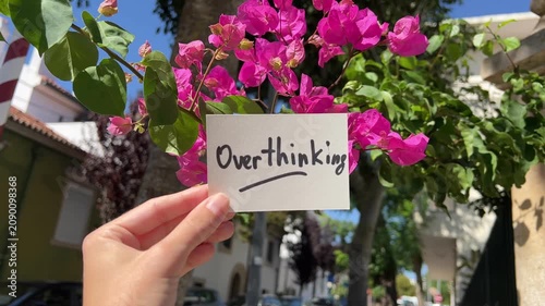 Overthinking - text with pink flowers and street on background, psychology issues concept