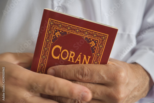 Person holding a coran, the holy book of islam, while practicing faith and devotion