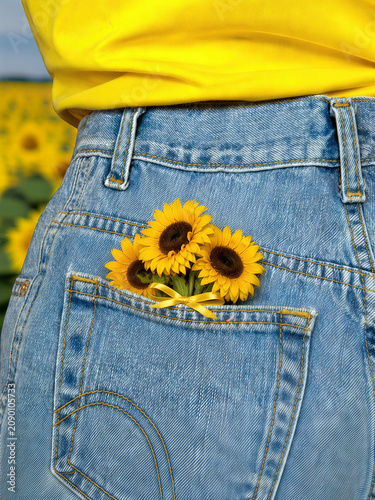 Bright yellow sunflowers tucked into a blue jean pocket, secured with a yellow satin bow