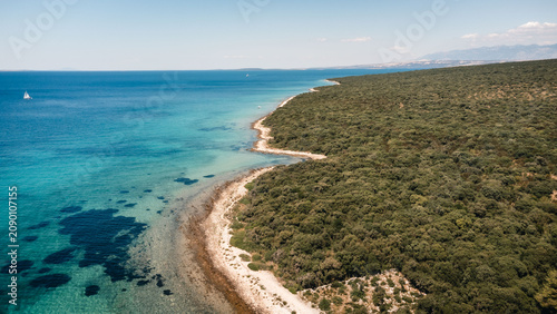 Tablou pe pânză Aerial coastline with turquoise sea meeting rugged rocky scrubland under clear s