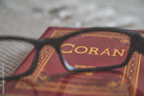 Reading glasses resting on a red coran book, representing islamic faith and devotion
