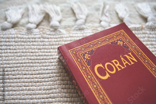 Coran book with ornate cover resting on a textured woven rug