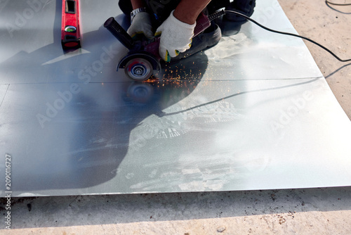 construction worker cutting concrete with a grinder on a construction site, focused close-up view of the ground level perspective with gray concrete and red tool handle.