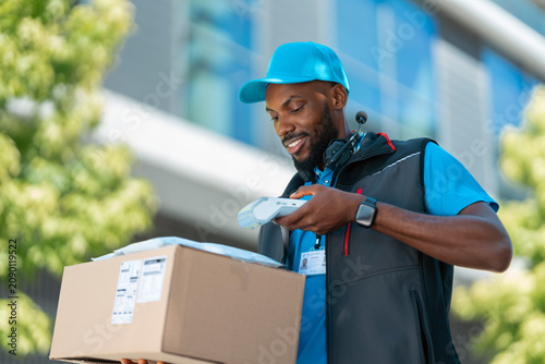 Bild auf Leinwand A delivery worker stands outside a modern building