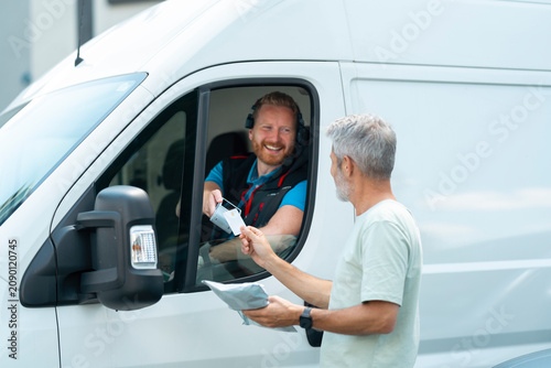 Customer makes a contactless payment using a handheld payment terminal while receiving a parcel from a courier.