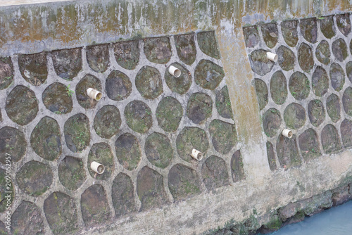 Canvastavla Concrete retaining wall structure with drainage pipes and stone pattern texture