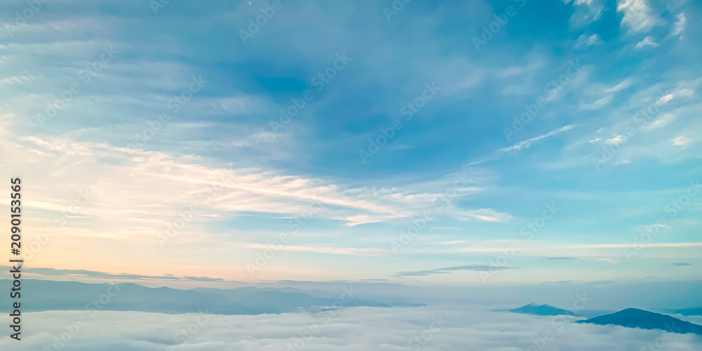 Fototapeta premium Beautiful sunrise landscape background with soft sea of fog over mountains and clear pastel turquoise blue sky for panoramic travel design