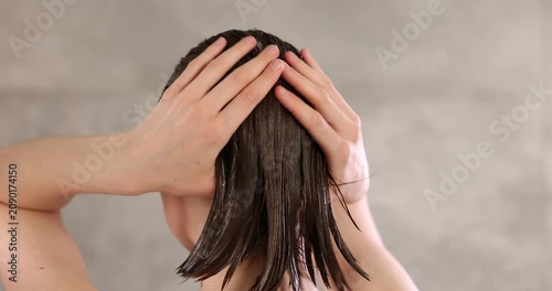 Woman applying mask onto her hair in bathroom, camera moving in