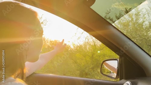 Young woman on a scenic drive, sunset magic illuminating her face, golden moment of joy, summer road trip energy, feeling the freedom of movement, reaching out to the sun, calm and relaxing trip