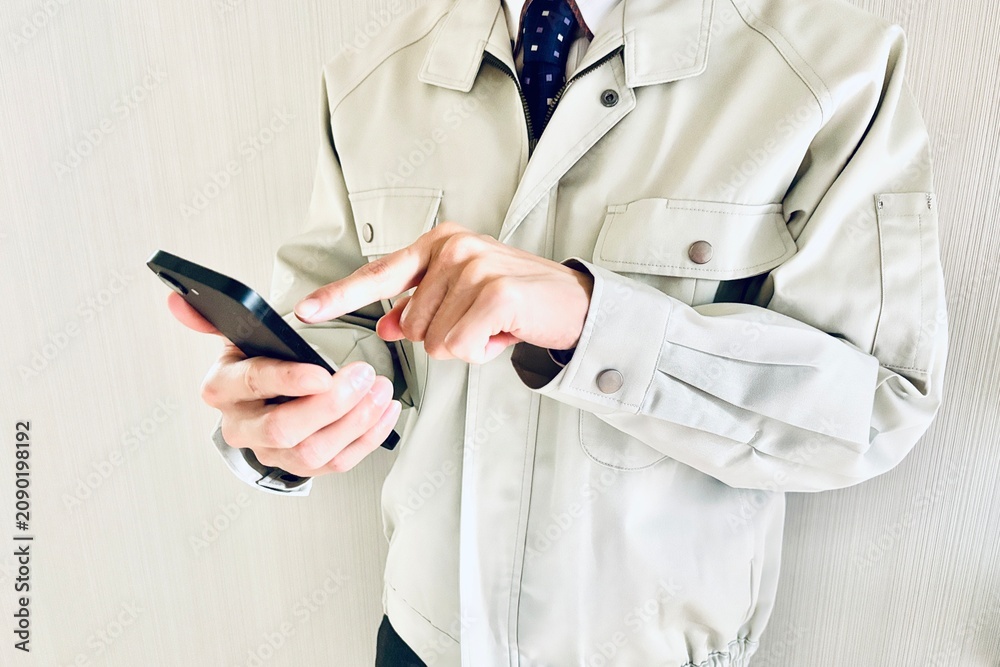 Obraz premium スマホを持つ作業着姿の男性ビジネスマン