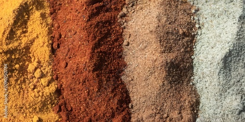 Macro close up of colorful spice powders arranged in gradient turmeric paprika cumin coriander filling entire frame